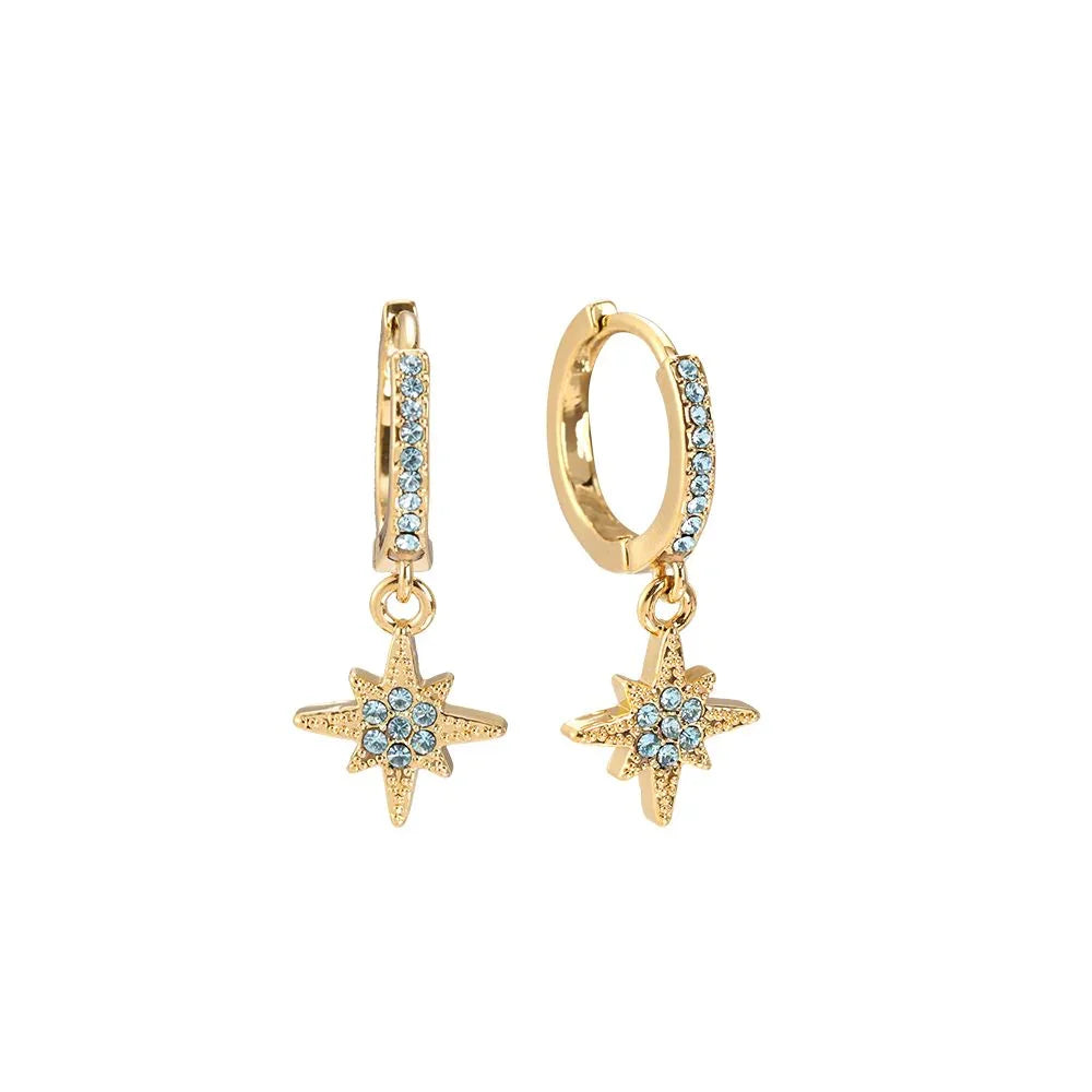 Goldene Creolen Ohrringe mit blauen Kristallen und Sternanhänger auf weißem Hintergrund