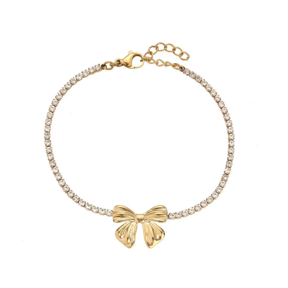 Goldfarbenes Armband mit Schleifenanhänger und funkelnden Kristallen auf weißem Hintergrund