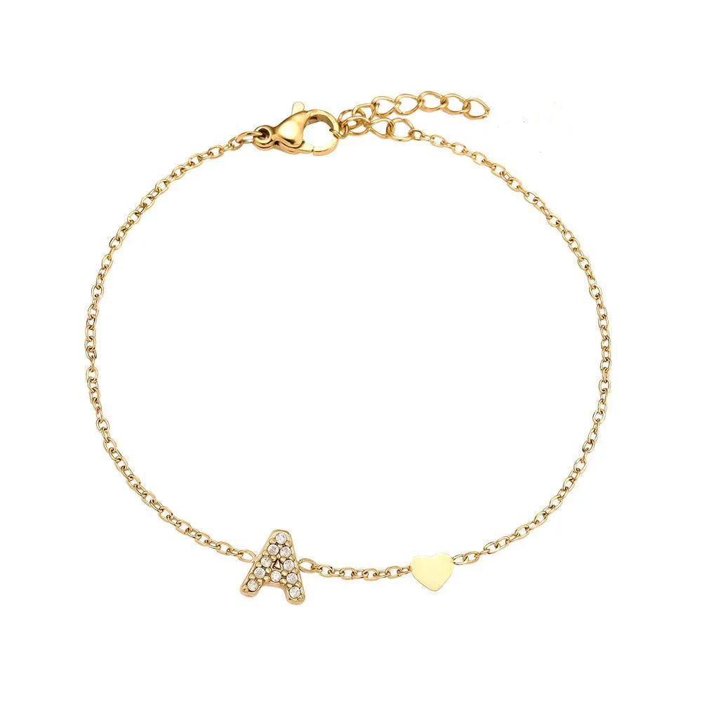 Goldfarbenes Armband mit glitzerndem Buchstaben A und Herz-Anhänger auf weißem Hintergrund
