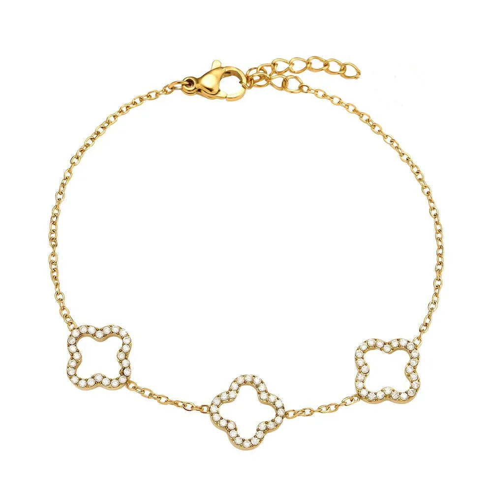 Feines goldfarbenes Armband mit drei vierblättrigen Kleeblatt-Anhängern besetzt mit kleinen weißen Kristallen