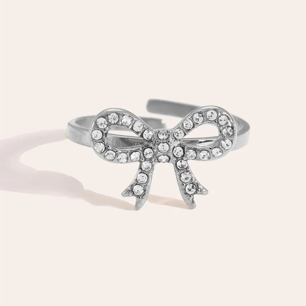 Silberner Ring mit funkelnder Schleifenform und klaren Kristallen, Nahaufnahme auf hellem Hintergrund