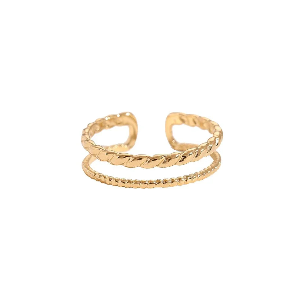 Offener goldener Ring mit gedrehtem und kugelbesetztem Design vor weißem Hintergrund