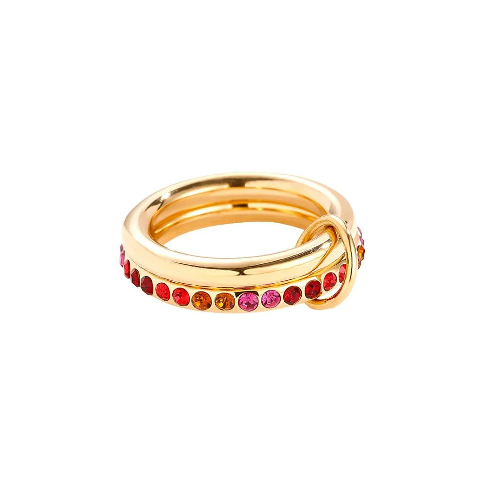 Goldener Ring mit bunten roten und pinken Schmucksteinen auf weißem Hintergrund