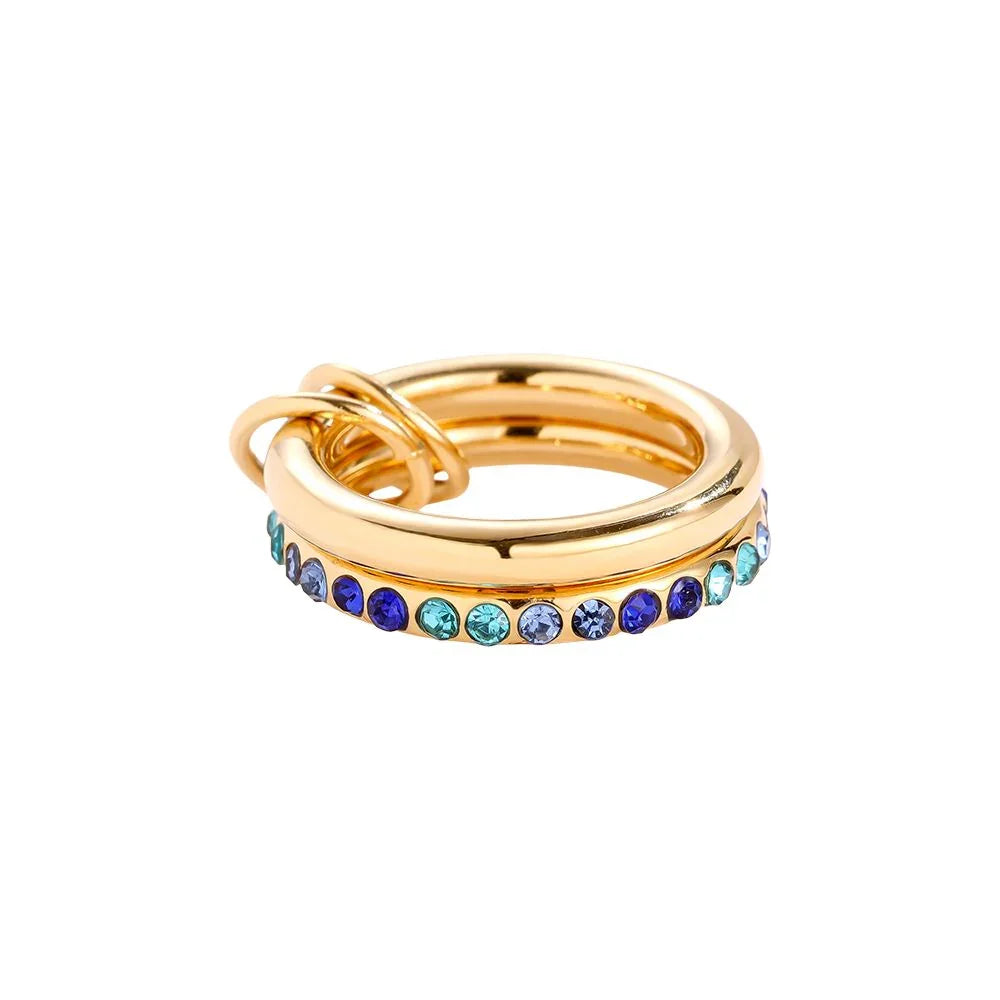 Goldfarbener Ring mit blauen und türkisfarbenen Kristallen auf weißem Hintergrund