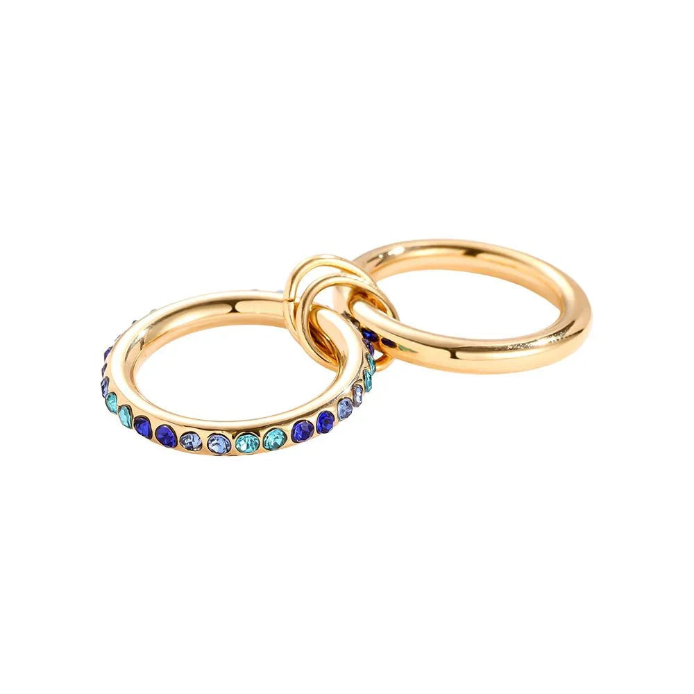 Zwei ineinander verschlungene goldene Ringe, einer mit blauen und türkisfarbenen Edelsteinen besetzt