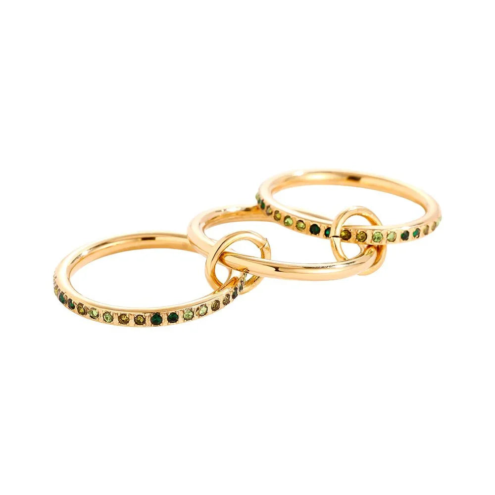 Drei goldene Ringe mit grünen Edelsteinen miteinander verbunden auf weißem Hintergrund