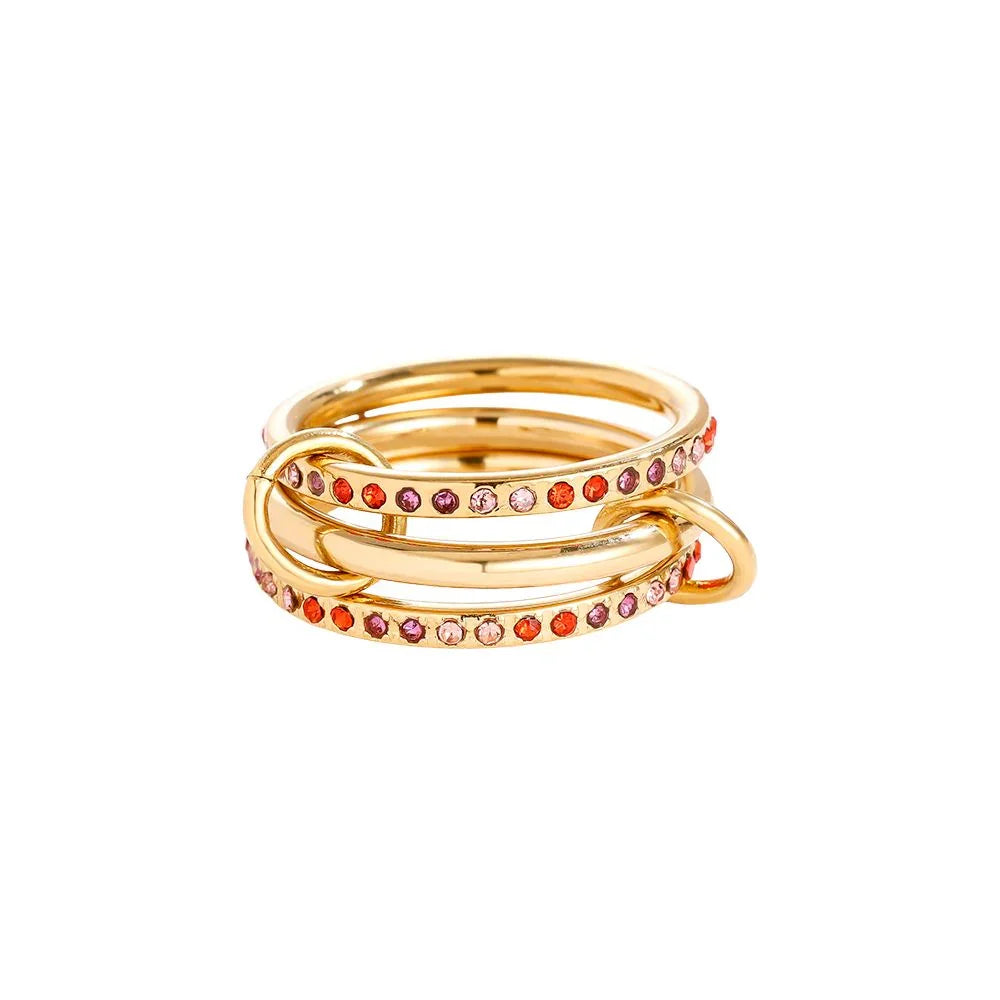 Goldener Ring mit pinken und roten Edelsteinen in modernem Design auf weißem Hintergrund