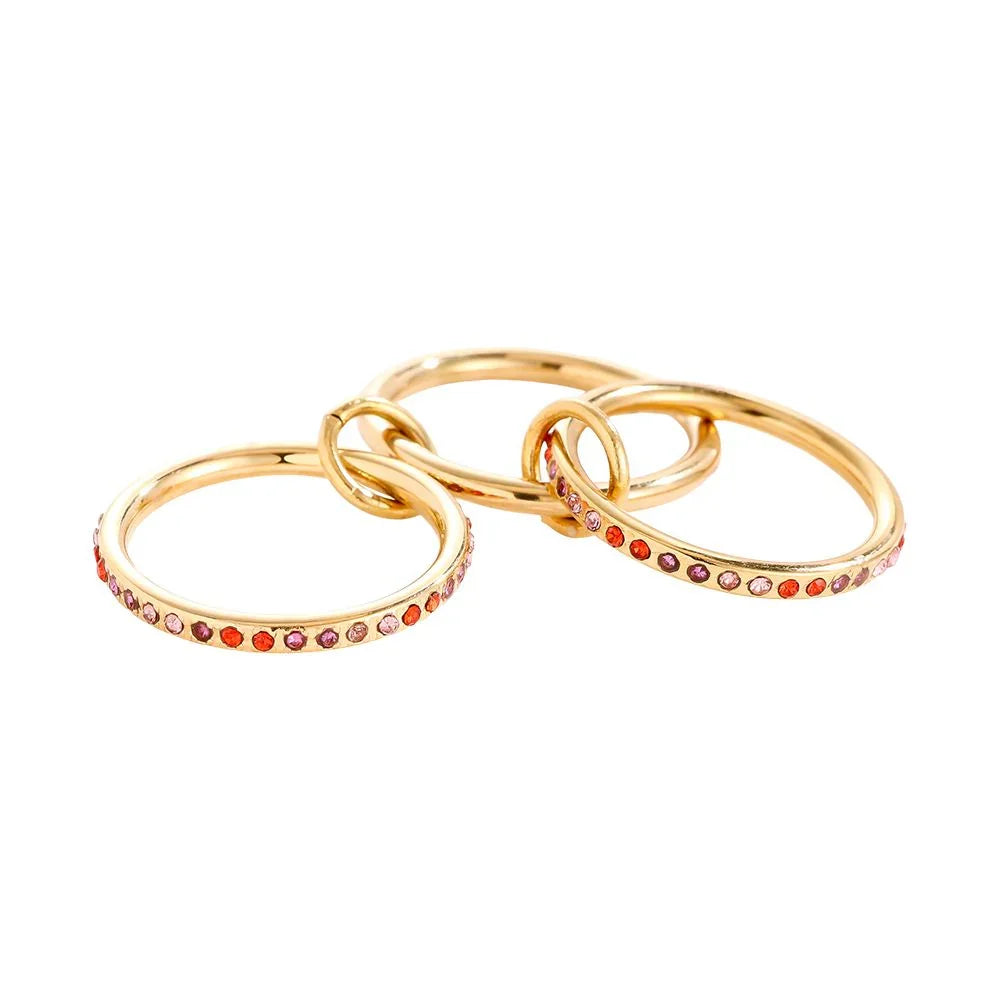 Drei goldene Ringe mit bunten Edelsteinen, verbunden und auf weißem Hintergrund