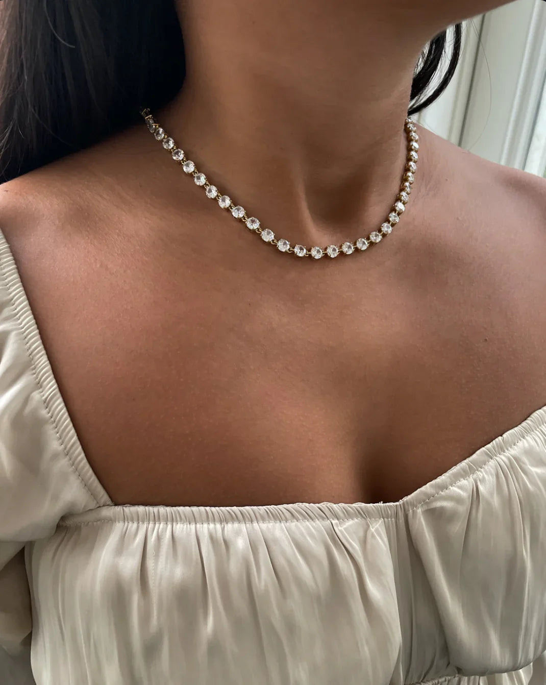 Frau mit eleganter Halskette aus klaren Kristallen und weißer Off-Shoulder-Bluse