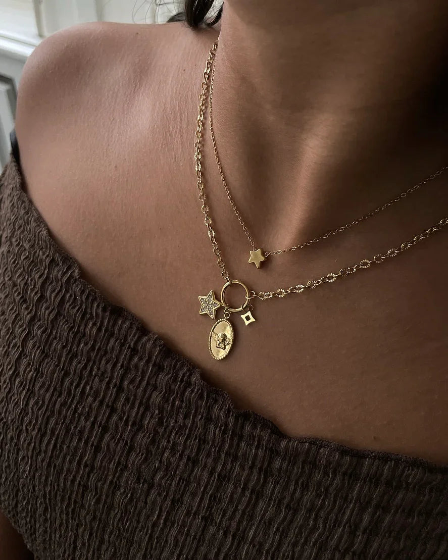 Damenoberkörper mit zwei goldenen Halsketten, eine mit Stern- und Münzanhängern, braunes Oberteil