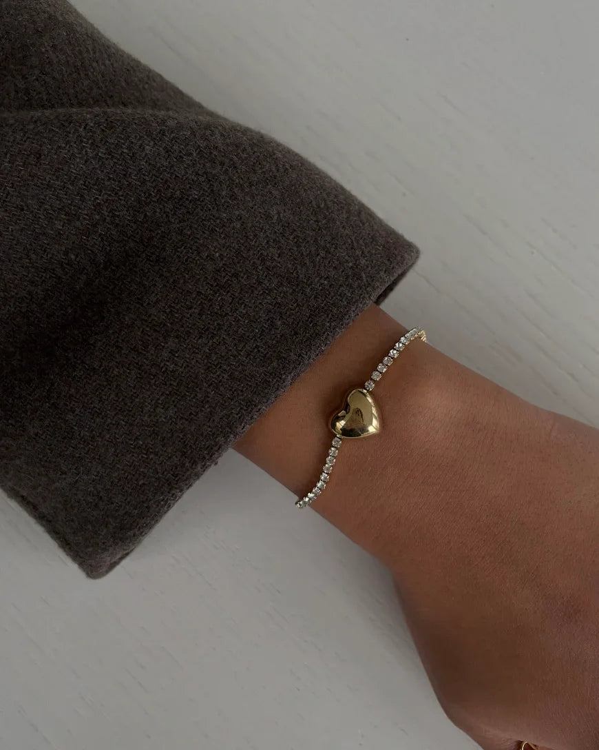 Elegantes Armband mit goldenem Herzanhänger und Glitzersteinen am Handgelenk