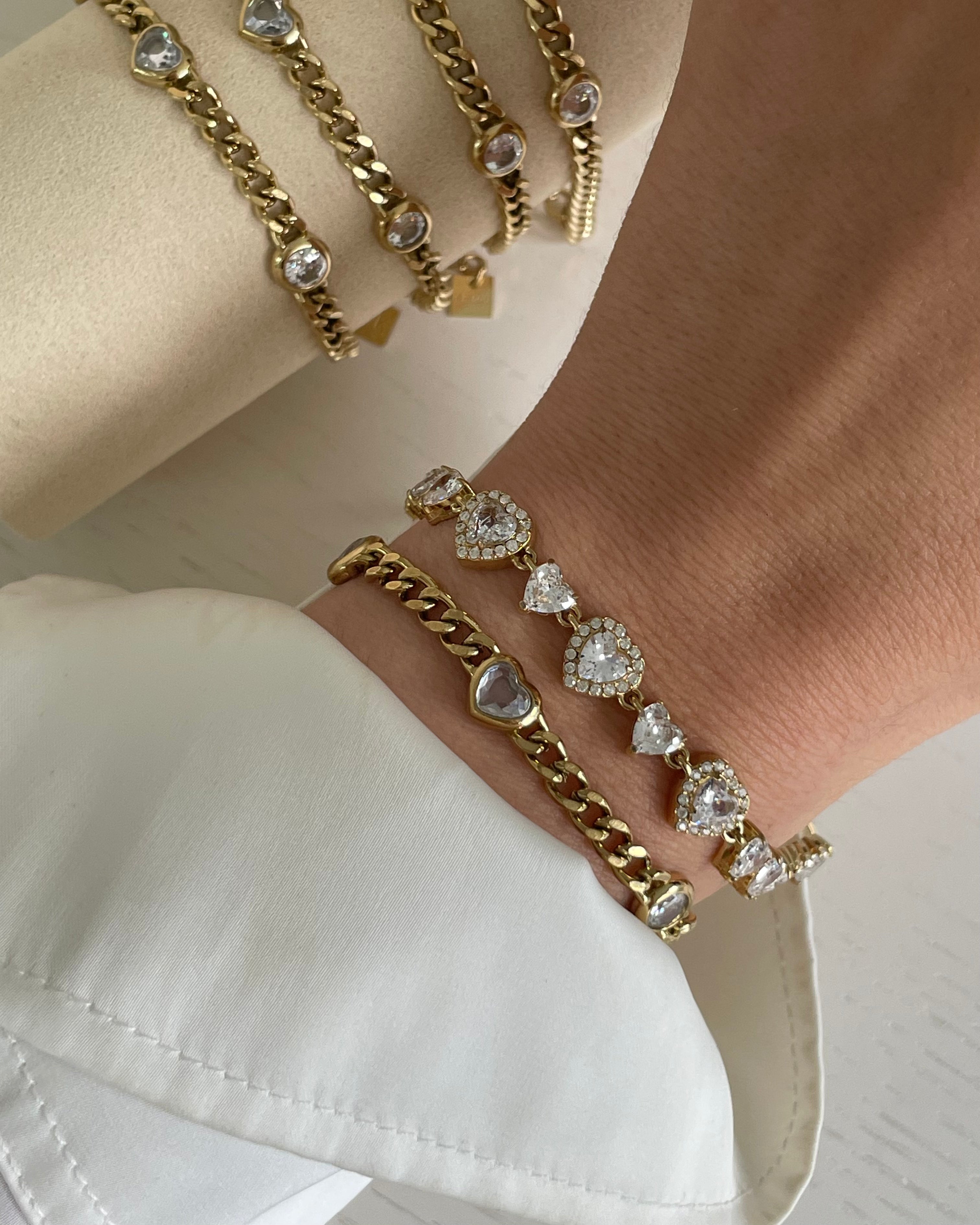 Goldarmbänder mit herzförmigen und runden Kristallen an Handgelenk und Displayhalter für eleganten Schmuck