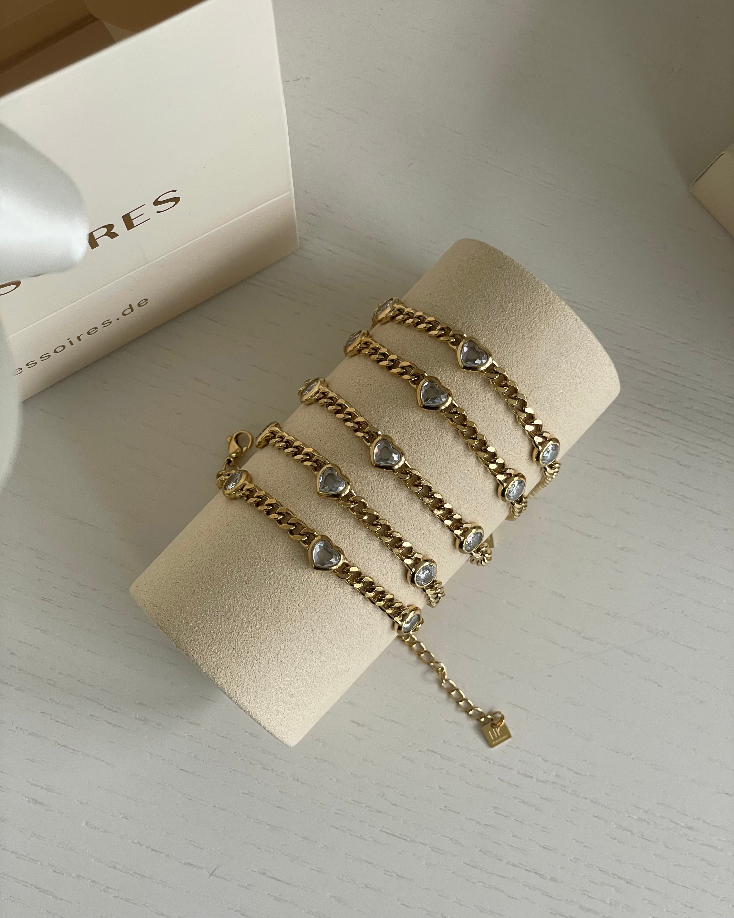 Goldarmbänder mit herzförmigen Anhängern auf samtbezogenem Schmuckhalter