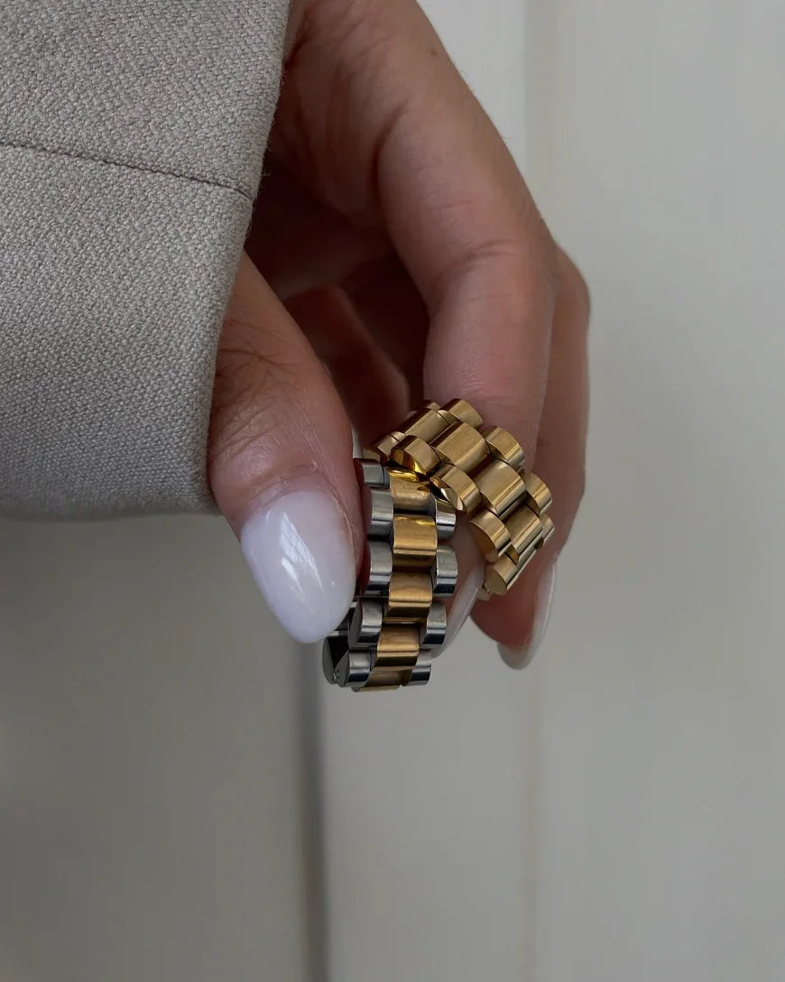 Hand hält zwei elegante Ringe aus goldfarbenem und bicolor Metall, Nahaufnahme