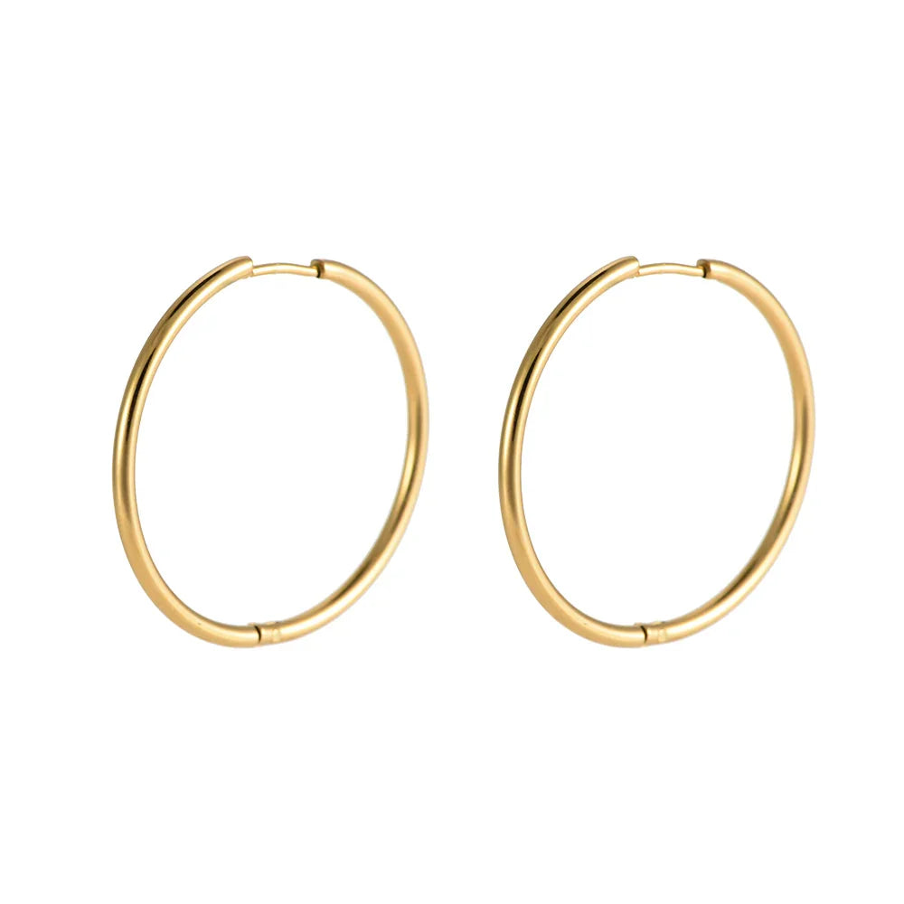 Goldfarbene Creolen Ohrringe aus Metall, schlicht, rund, glänzend vor weißem Hintergrund