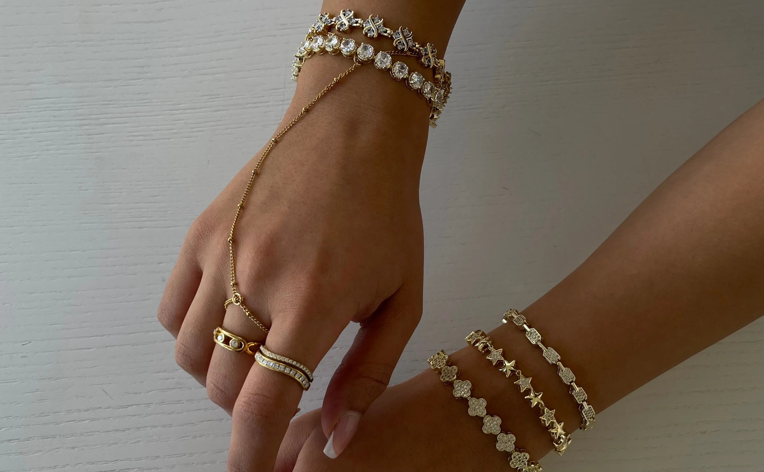 Goldfarbene Handkette, Ringe und verschiedene goldene Armbänder mit funkelnden Steinen auf brauner Haut